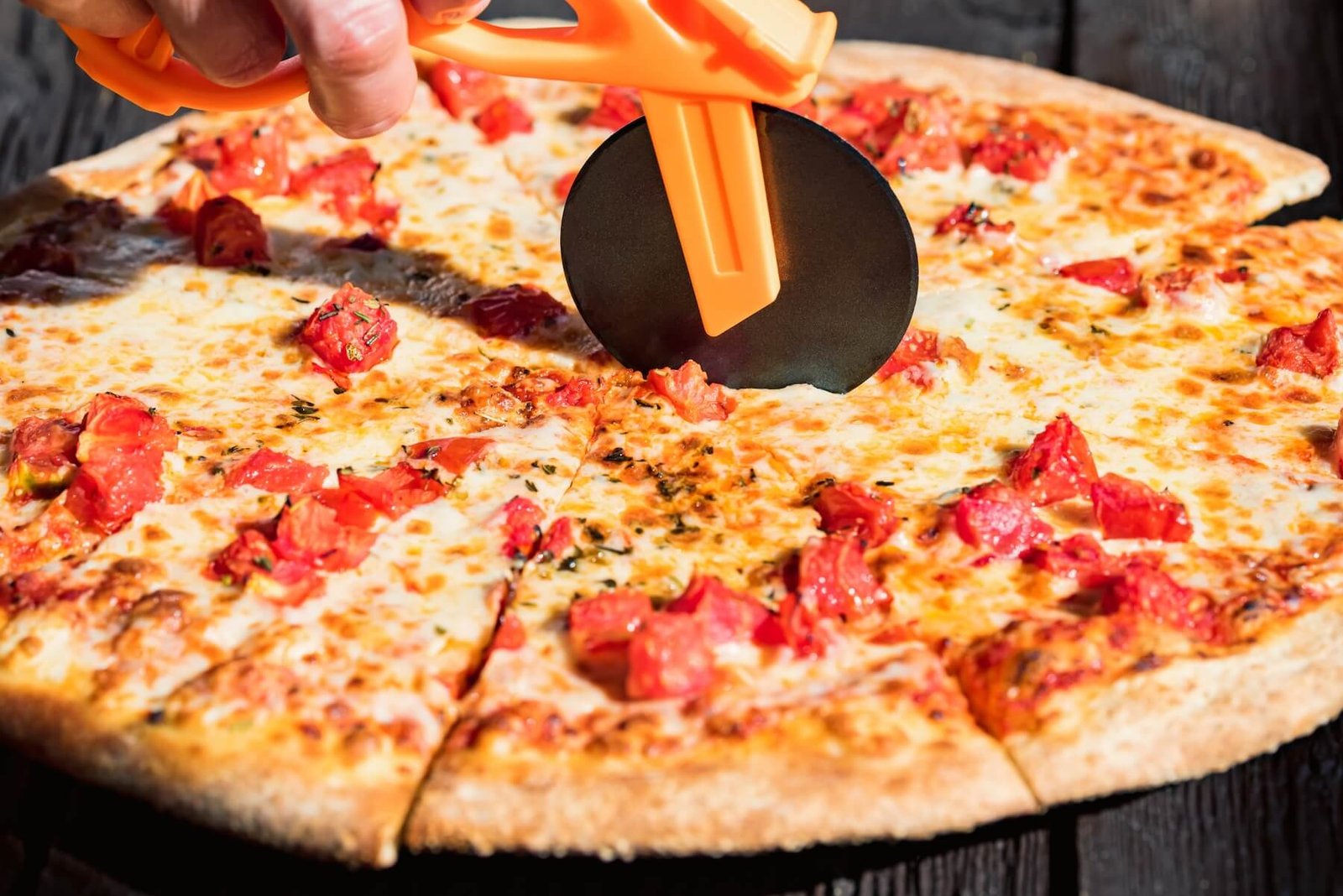 Fresh pizza being sliced with a pizza cutter